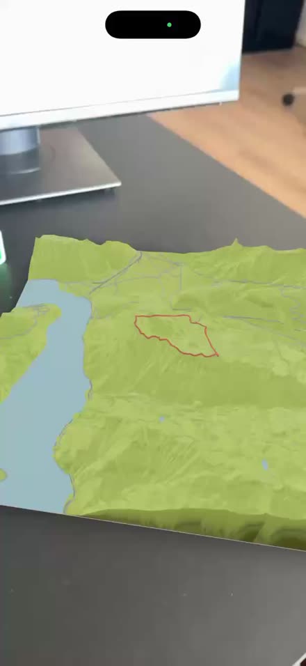 A terrain model with a route on it, shown in augmented reality on an iPhone in a real room.